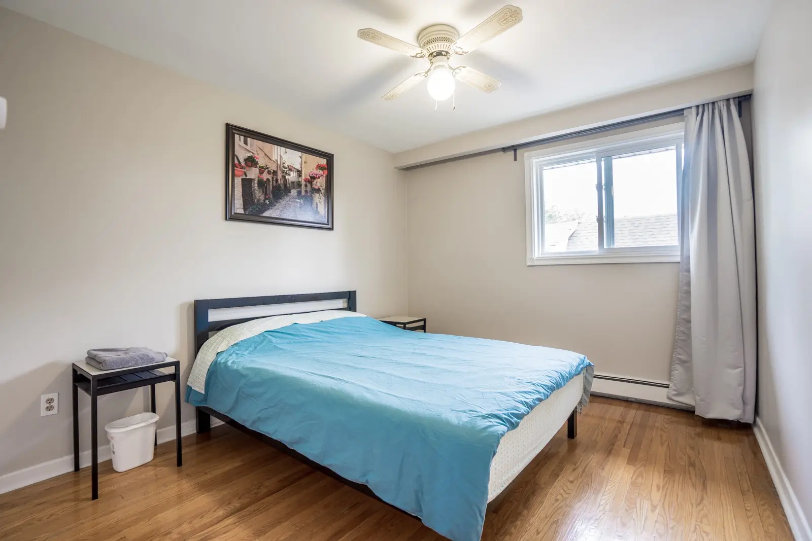 Fully furnished bedroom with queen bed and large window